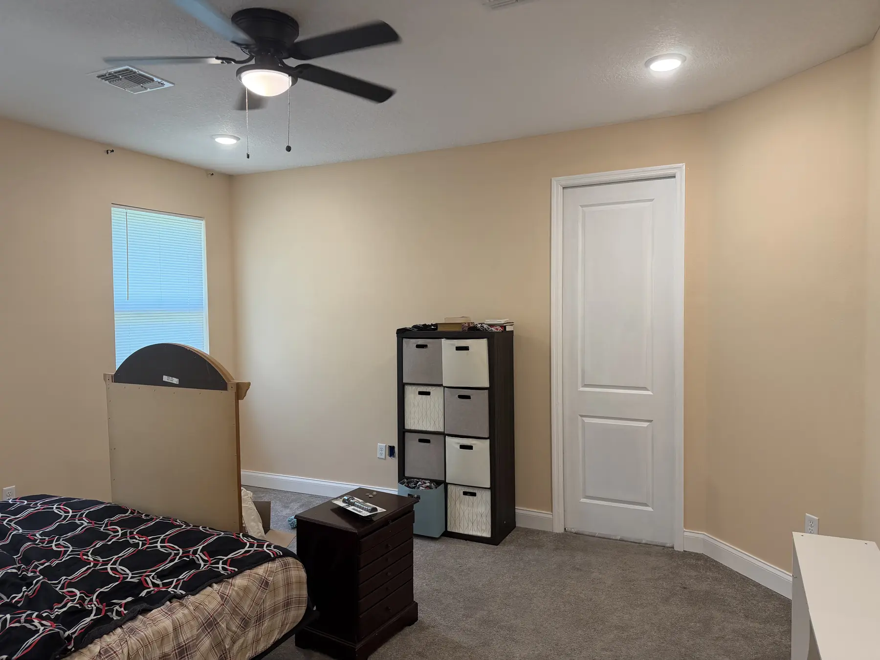 Guest bedroom repainted in a warm neutral with a white interior door and painted ceiling