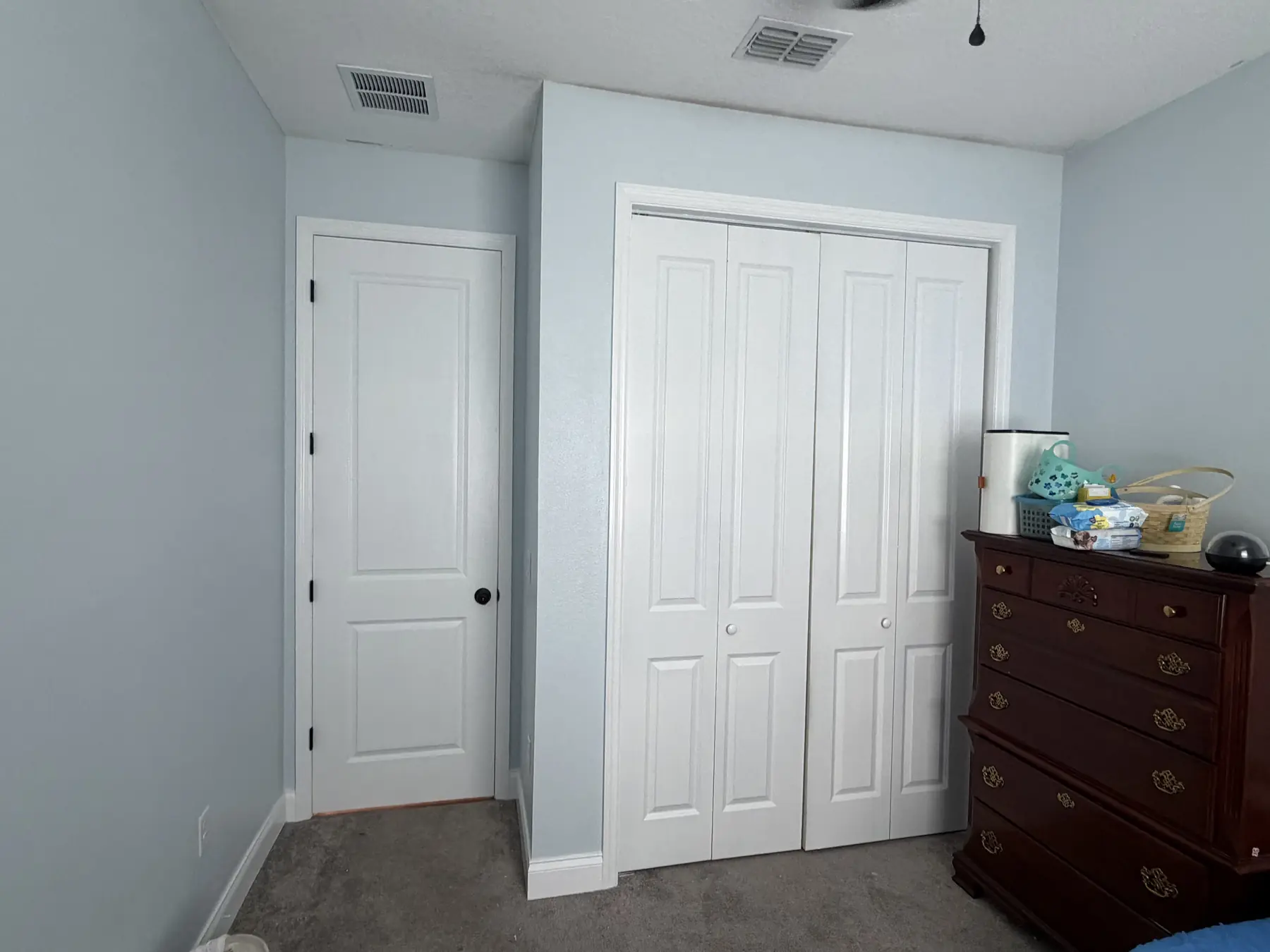 Bedroom with soft blue-gray painted walls and crisp white closet doors and baseboards