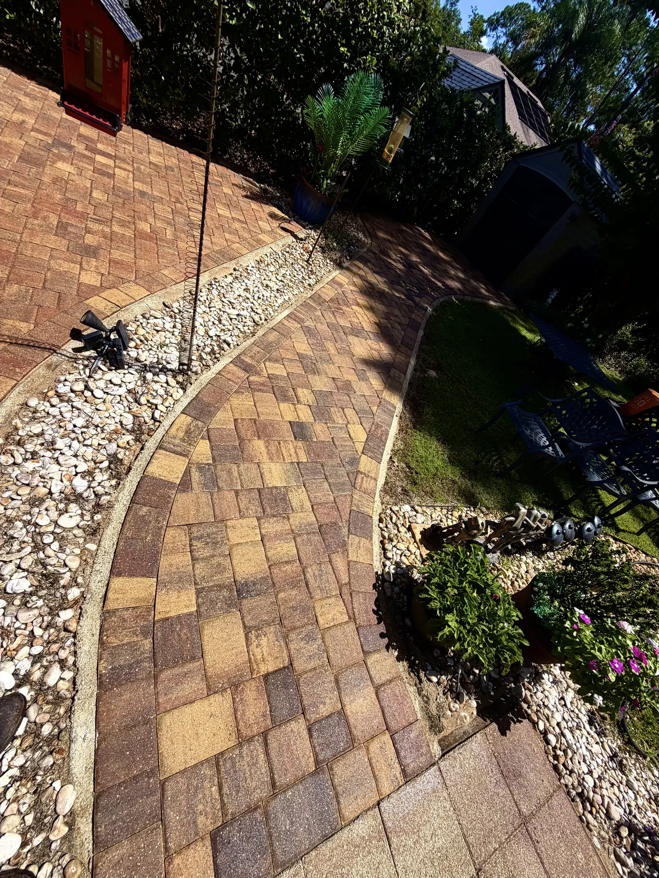 Restored curved paver walkway bordered by white stone and landscaping
