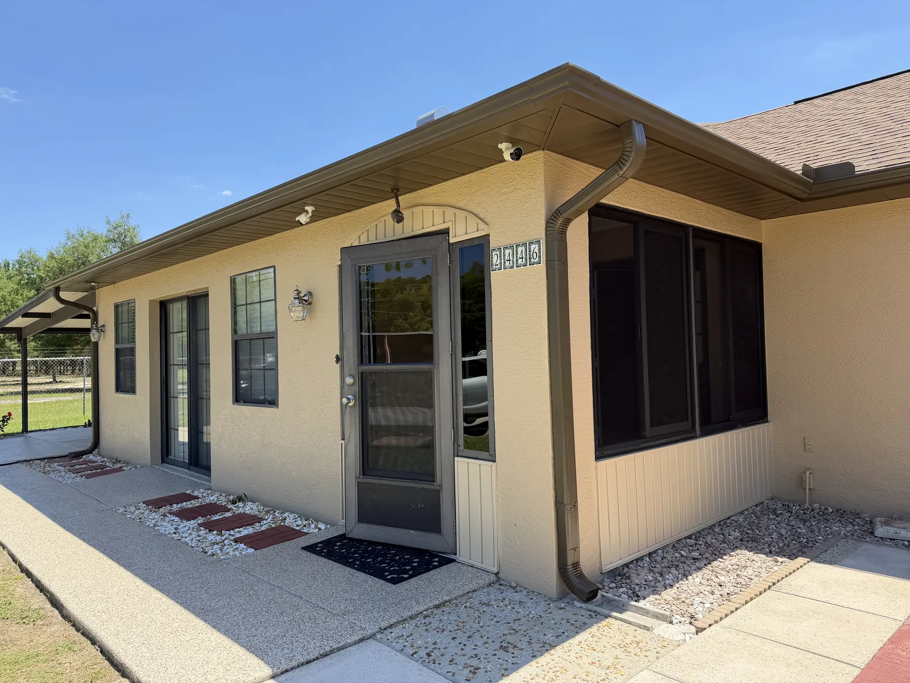 Building entry with newly painted cream stucco walls, brown soffit and fascia, and painted door trim