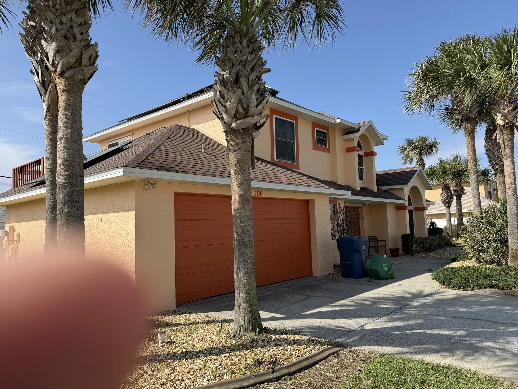 Freshly cleaned two-story garage exterior framed by palm trees