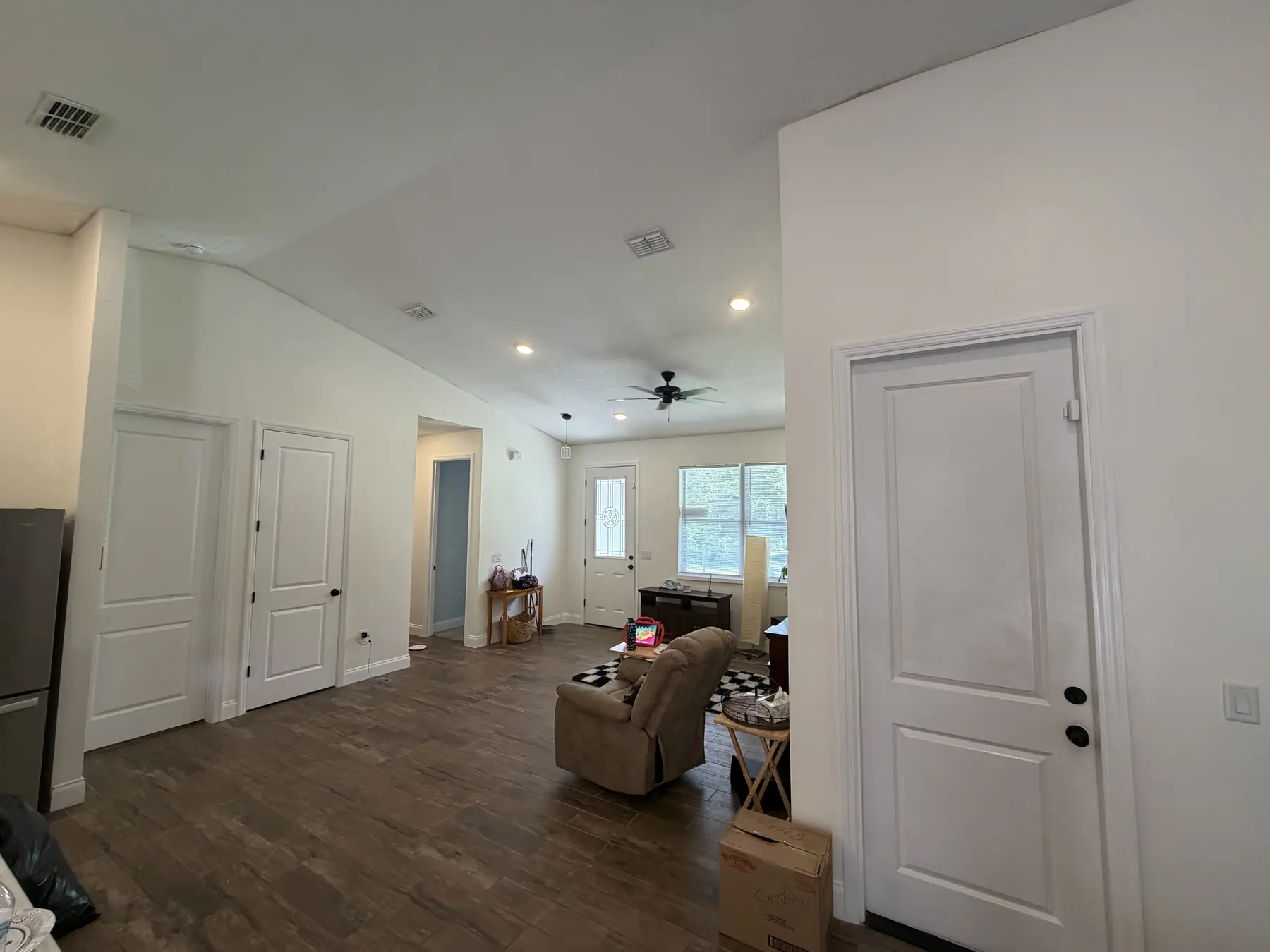 Open living area with freshly painted white walls, vaulted ceiling, and interior doors