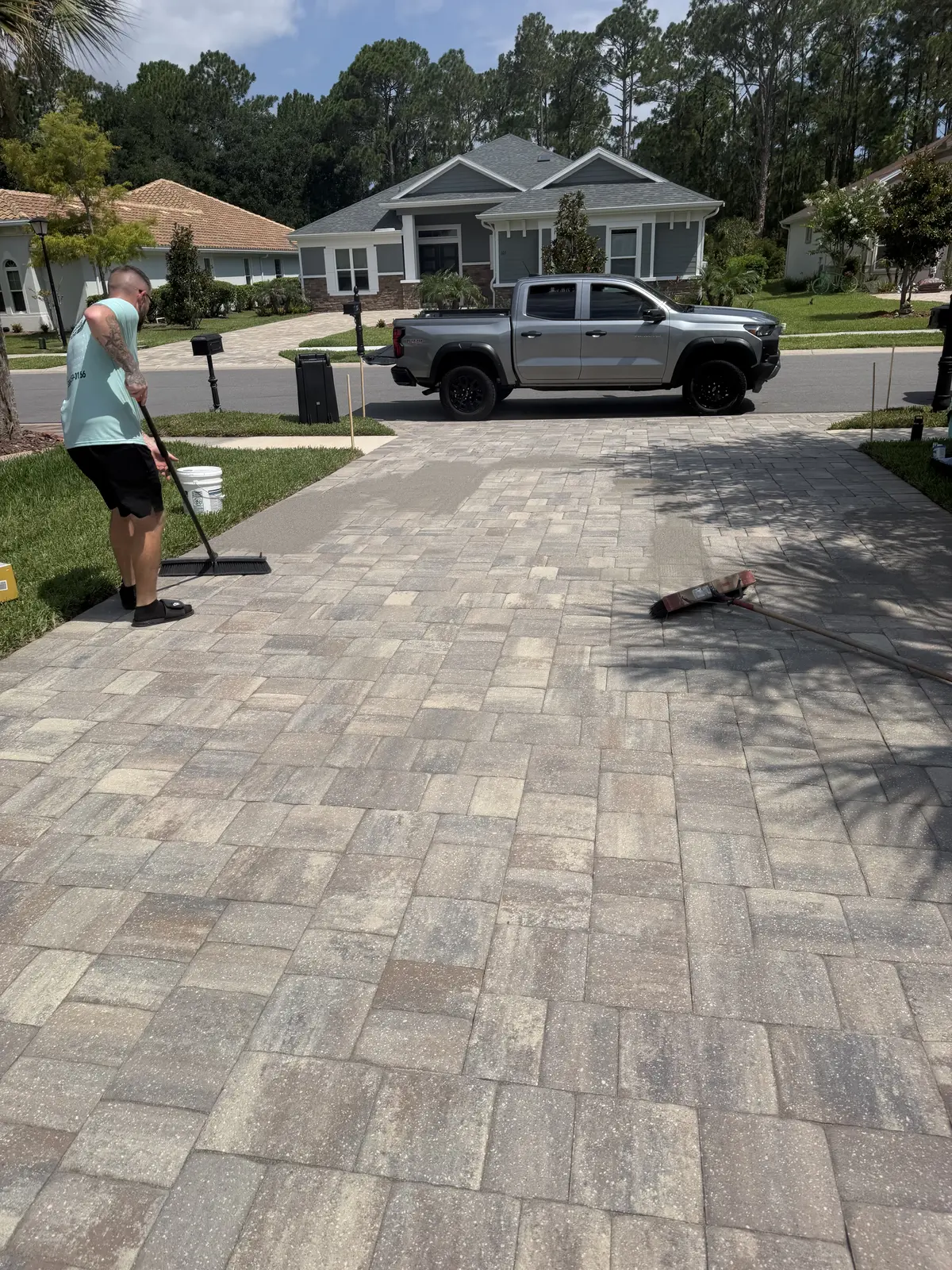 Technician cleaning a residential paver driveway