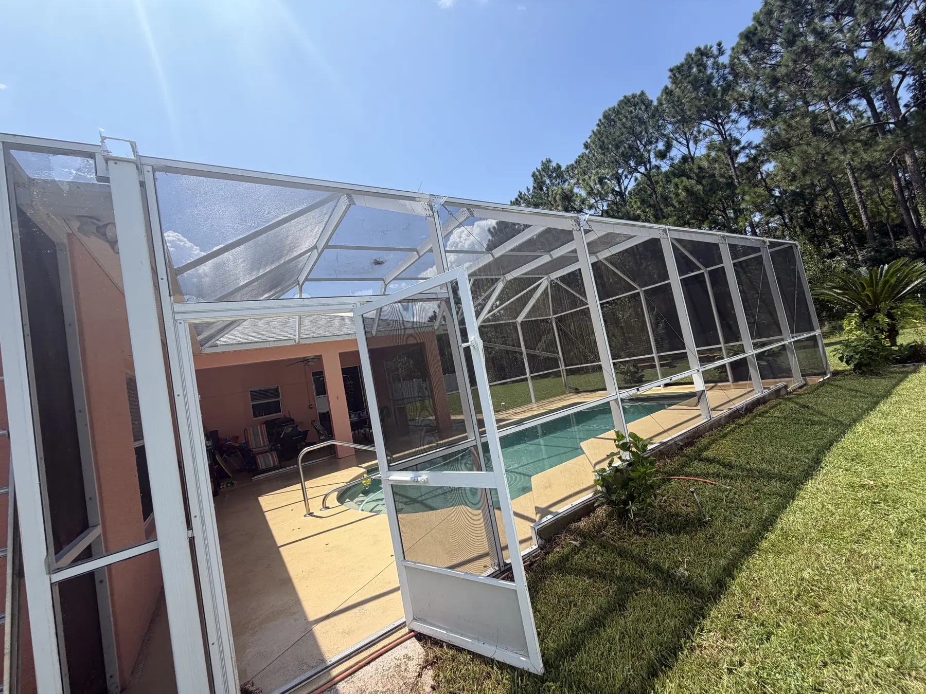 Clean white pool screen enclosure viewed from the backyard
