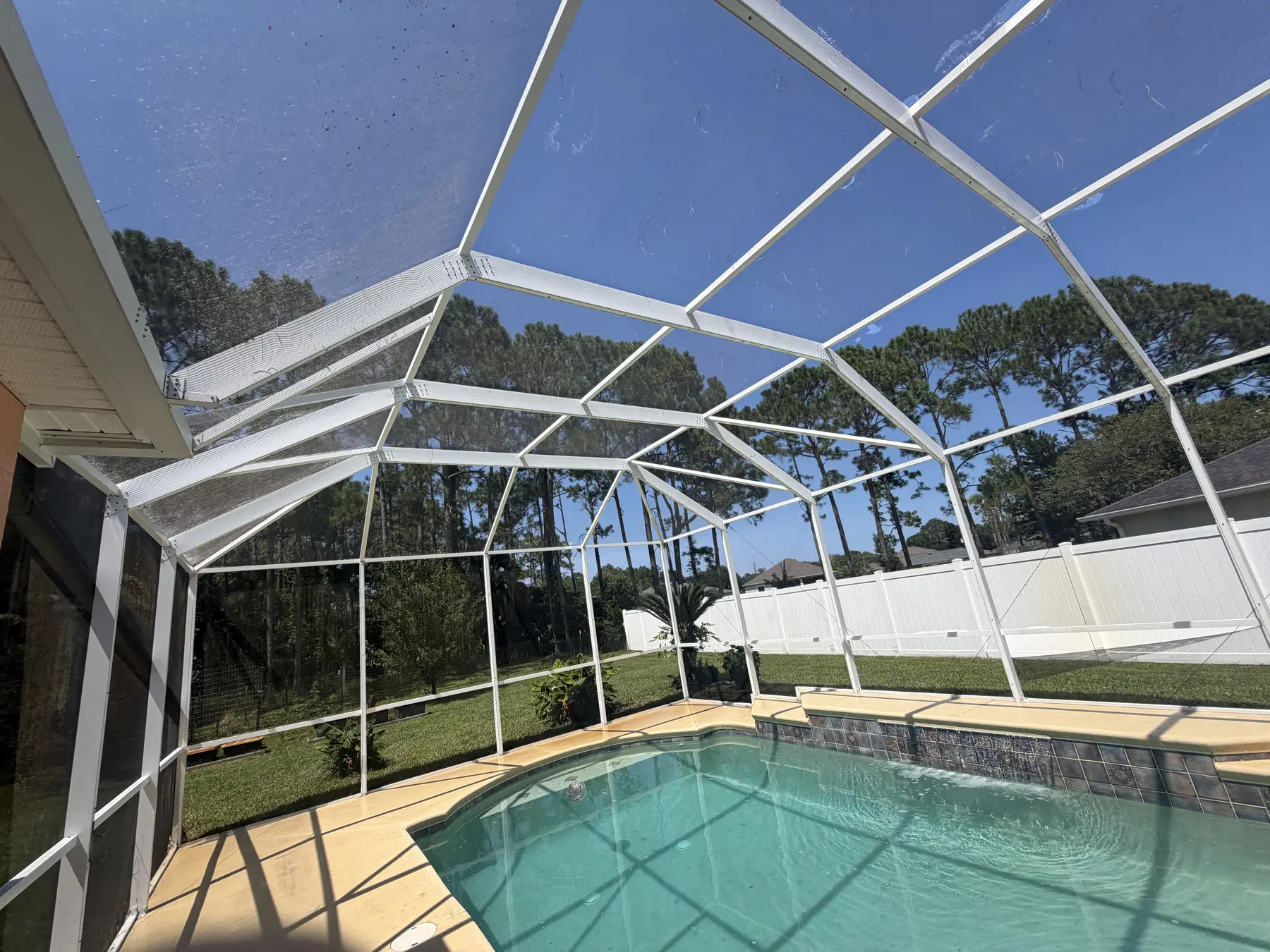 Clean pool screen cage and bright white framing under a blue sky