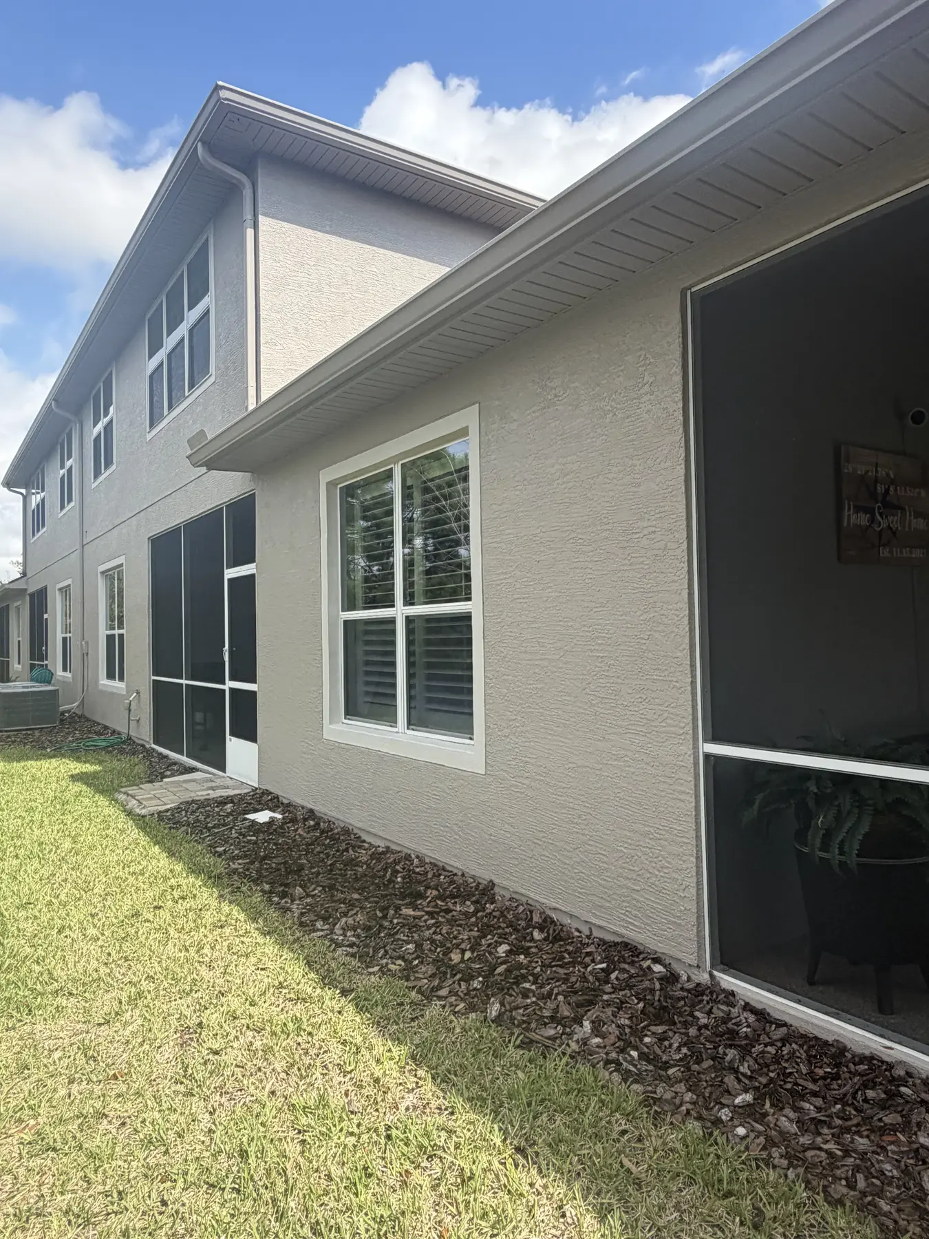 Clean two-story stucco side exterior beside a screened patio
