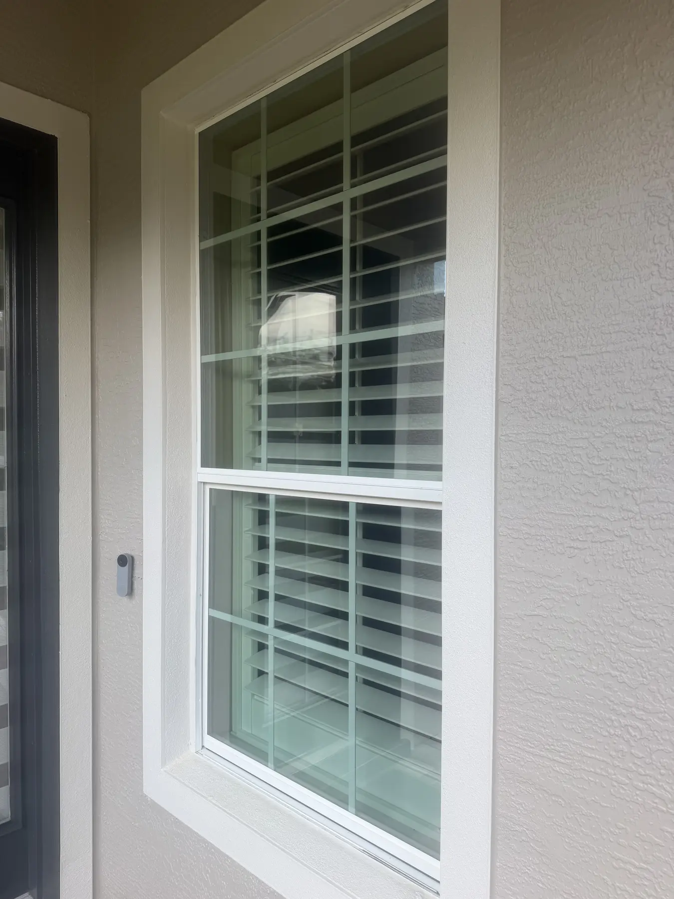 Compact exterior security light installed beside a residential window